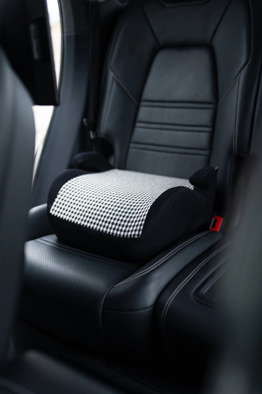 Pepita Kindersitz in schwarz-weiß on car seat, offering stylish and secure seating for children in vehicles.