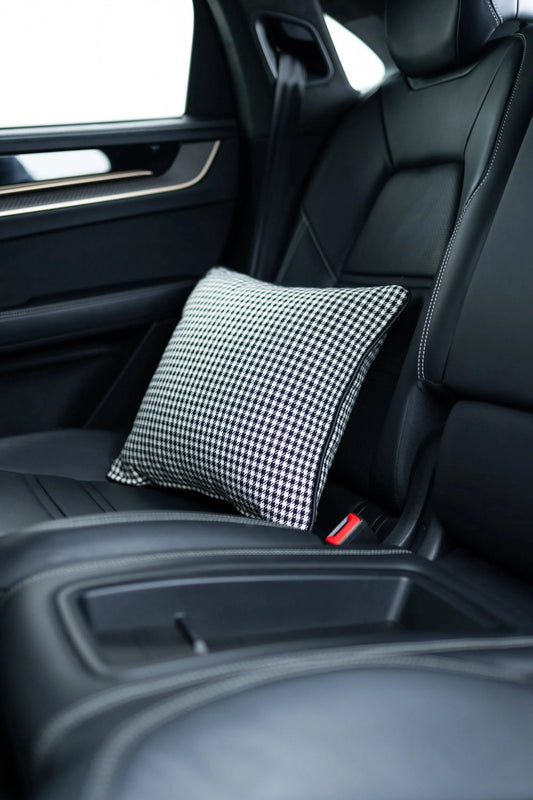 Pepita Kissen für Porsche in schwarz-weiß, elegant auf einem schwarzen Autositz platziert, ideal für stilvolle Autoinnenrä...